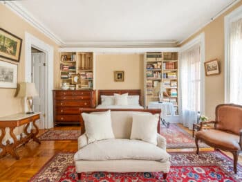 Bedroom with brown sleighbed. White Bedding. Red Rug.