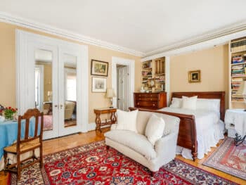 Bedroom with red rug, brown sleigh bed, round table with blue table cloth.